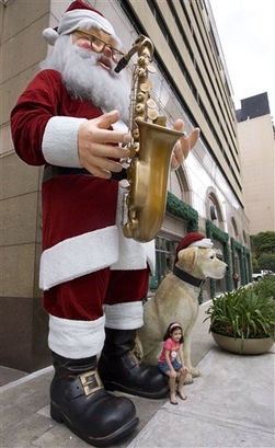 A girl sits next to a figure of Santa Claus on display at a ...