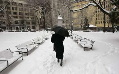 A pedestrian walks through a snow covered park in downtown Portland, ...